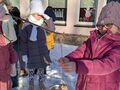 dziewczynka w ubraniu zimowym zawiesza na gałęzi szyszkę oblepioną nasionami