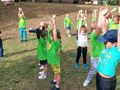 Dzieci w zielonych koszulkach ćwiczą na świeżym powietrzu