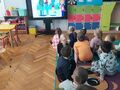 dzieci siedzą na dywanie oglądają film edukacyjny o niepełnosprawności