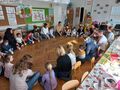 dzieci z rodzicami siedzą w kółku mają przed sobą kubeczki plastikowe